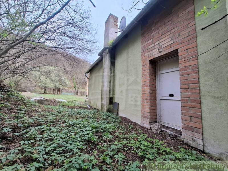 The exterior of the cottage in Chľaba with a green facade and a brick element.