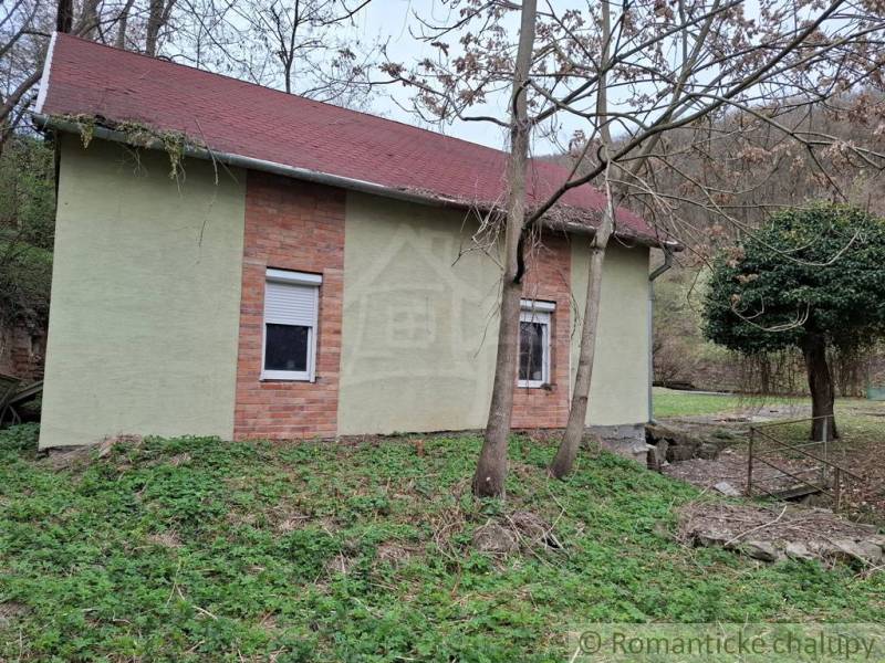 A cottage in the village of Chľaba with brick details and a red roof, surrounded by nature.