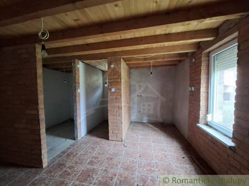 Interior of a cabin with brick walls, a wooden decor floor, and exposed electrical wiring.