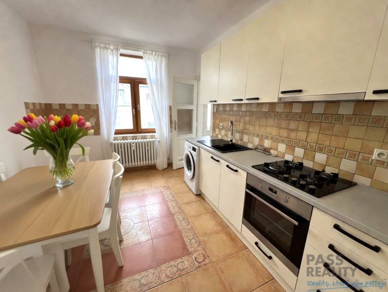 A kitchen in a 2-room apartment with flowers on the table and ceramic tiles.