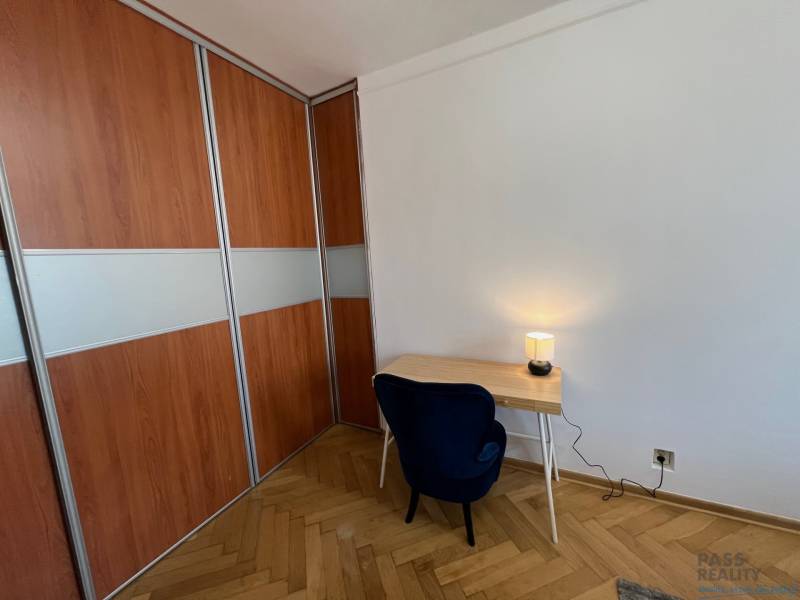 A room with a desk, chair, wood-patterned floor, and built-in wardrobe.