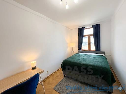 Bedroom in a 2-room apartment with a bed, table, and lamp, floor with wooden decor.