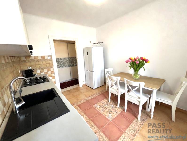 Kitchen in a 2-room apartment with a dining table, sink, and flowers on the table.