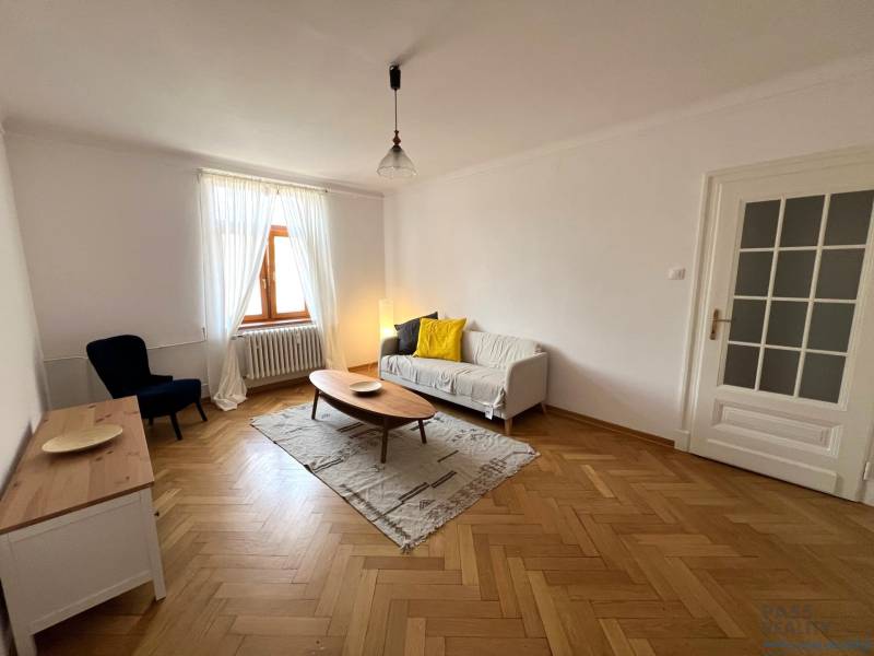 Living room in a 2-room apartment with a wooden decor floor, sofa, and table.
