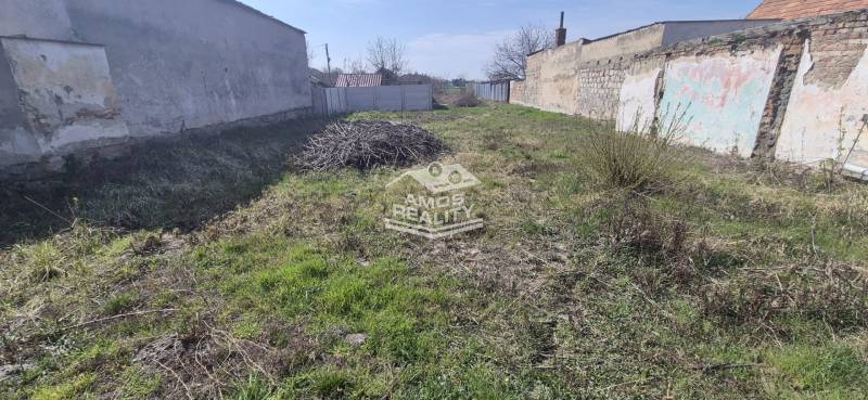 A plot on Družstevná Street in Malacky, designated for residential use, surrounded by older walls.