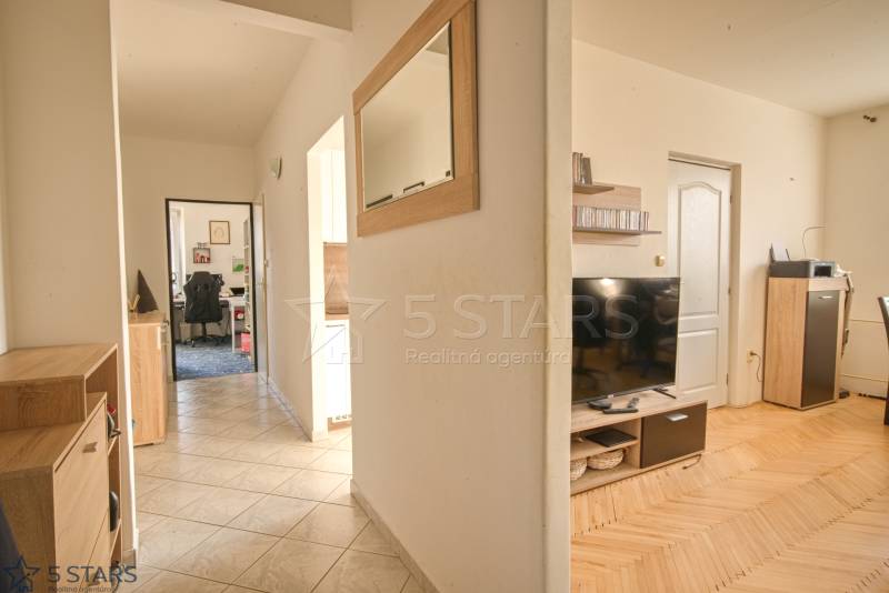 A hallway in a 3-room apartment with a wooden decor floor and furniture.