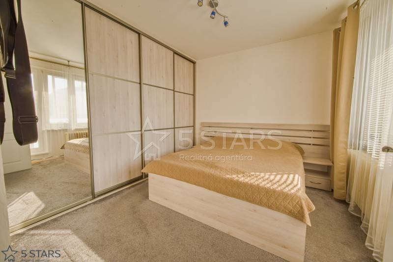 A bedroom with a large built-in wardrobe and a bed in a 3-room apartment.