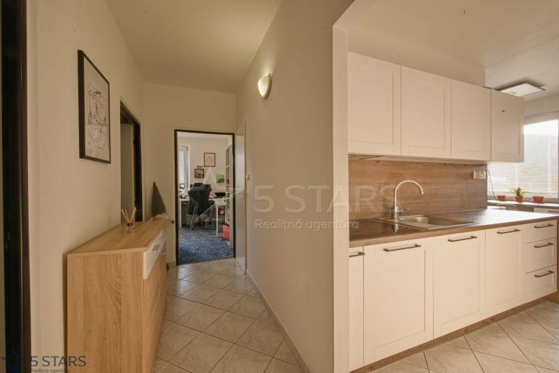 A kitchen in a 3-room apartment with white cabinets and a built-in sink.
