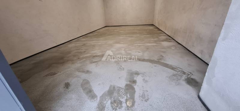 An empty garage with a concrete floor and tire marks.