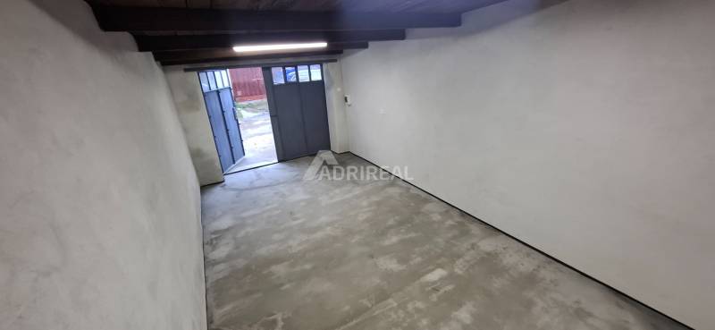 An empty garage with a concrete floor and a wooden ceiling.