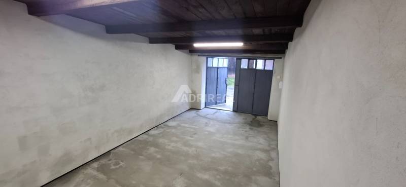 The interior of a garage with white walls and a metal door.