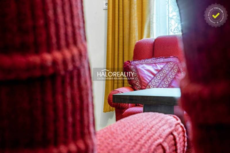 Red armchairs with patterned cushions and yellow curtains in the living area of a family house.