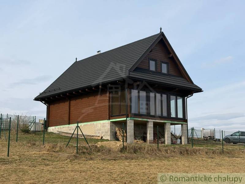 A family house in Lom nad Rimavicou with wooden cladding and a glass veranda.