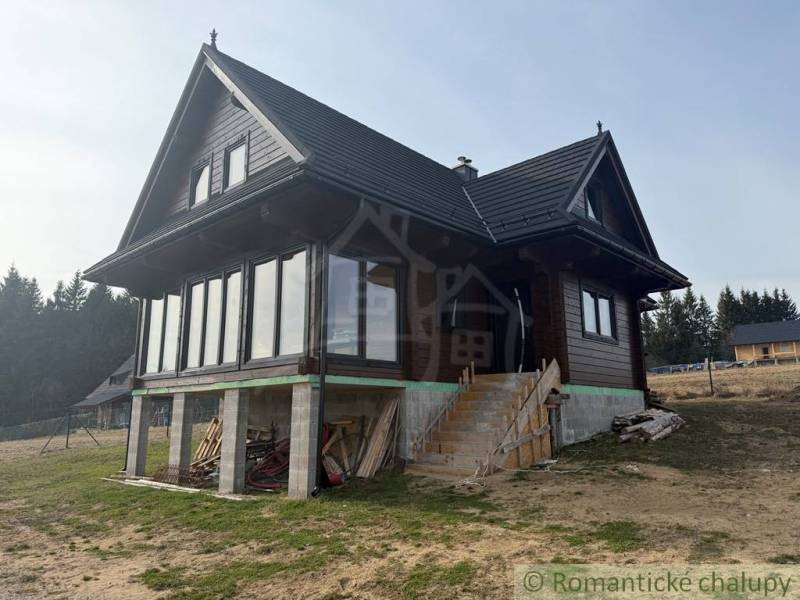 A wooden family house in Lom nad Rimavicou, with large glass sections and a sloped roof.