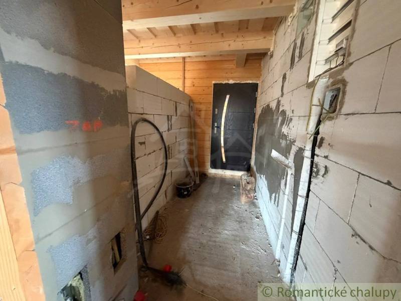 A construction in a family house with unfinished walls and wooden ceilings.