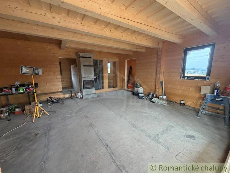 The interior of a family house with wooden walls and a tiled stove, an unfinished room.