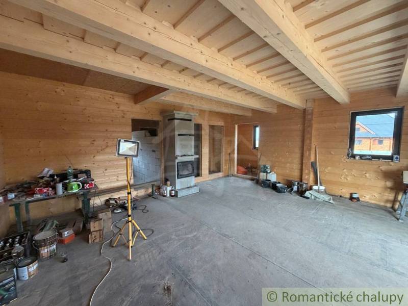 Wooden interior walls and a fireplace in a family house with unfinished flooring.