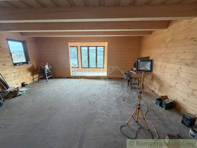 Interior of a family house with wooden paneling, incomplete flooring, and portable light.