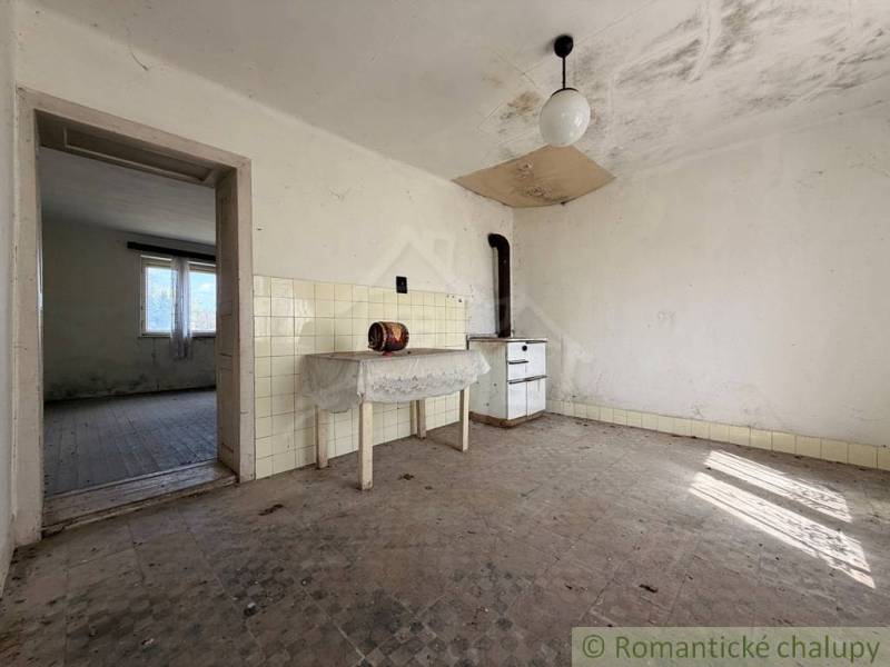 Abandoned room of a family house with simple furnishings and tiled walls.
