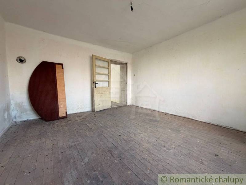 A room in a family house with an exposed floor featuring a wooden decor and white walls.