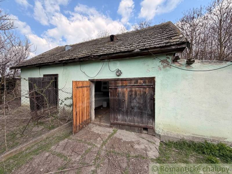 An old house with an open wooden gate, fenced in Čalovec.