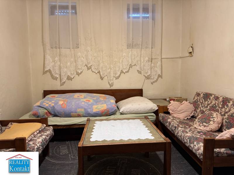 Living room in a family house with sofas, a coffee table, and lace curtains.