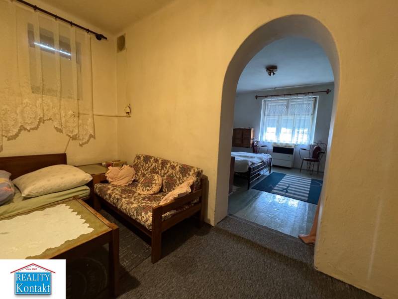 A room with simple furniture and an arched passage in a family house.