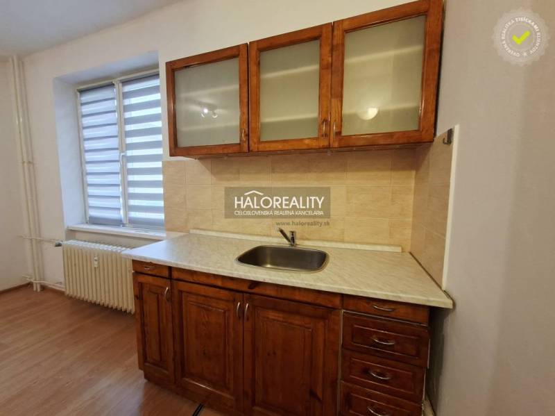 Kitchen unit with a sink and cabinets in a studio apartment with a wooden decor floor.