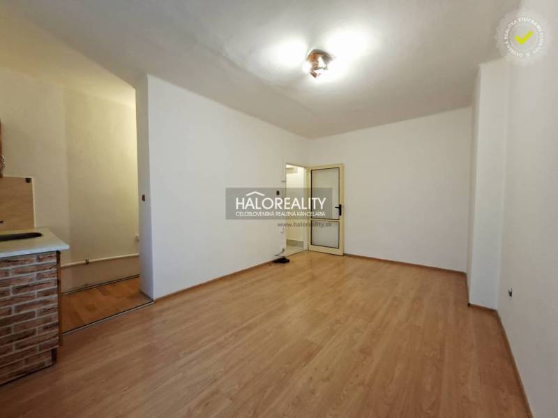 A studio apartment with a wooden floor and simple furnishings.