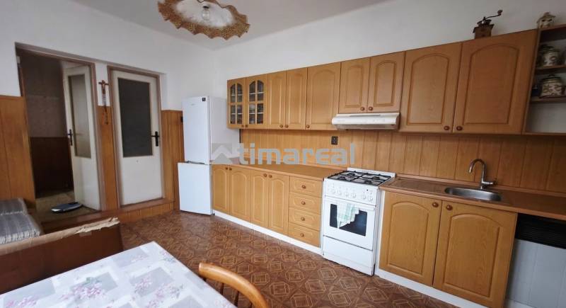A kitchen in a family house with wooden decor, a stove, and a refrigerator.