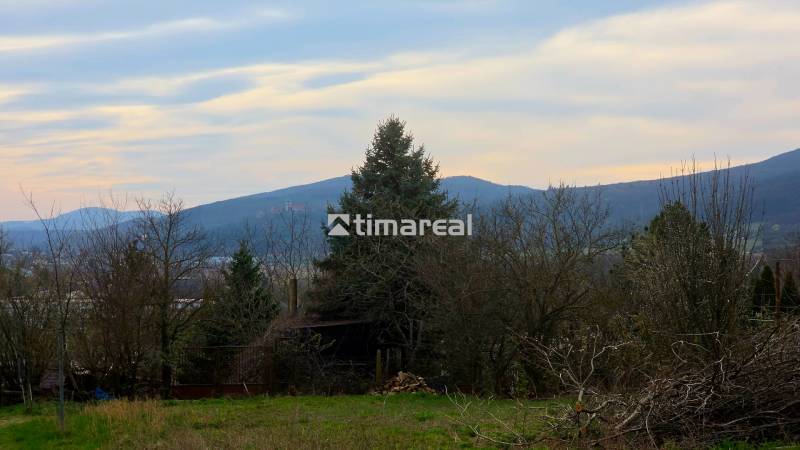 The garden of a family house in Trstín with a view of the hilly landscape and greenery.