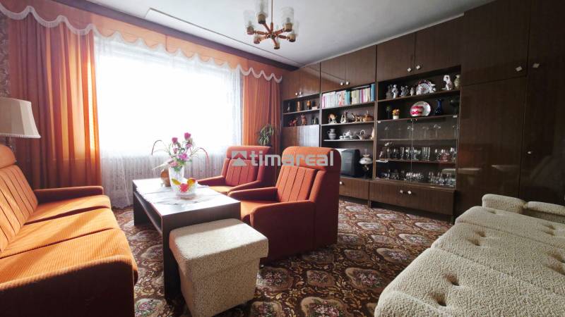 A living room in a family house with orange armchairs and dark furniture.