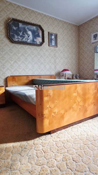 A bedroom in a family house with a wooden bed and paintings on the walls.