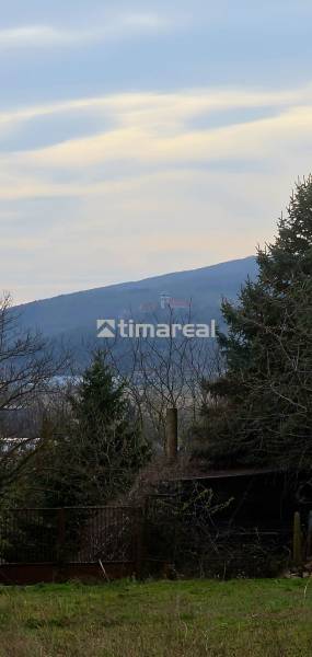 View of the hills from a family house in Trstín, with trees and roofs visible.