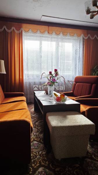 A living room in a family house with orange furniture and curtains.