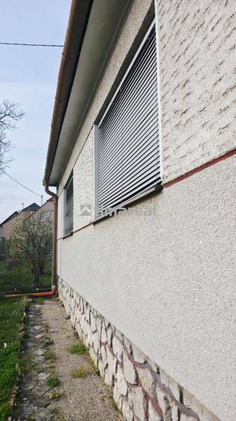 Exterior of a family house in Trstín with a stone plinth and shutters on the windows.