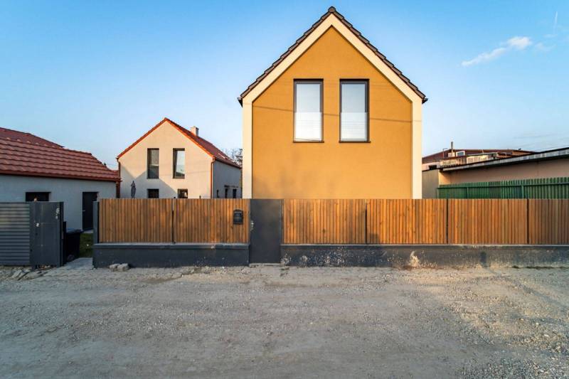 Front view of a fenced family house in Poprad with brown facade elements.