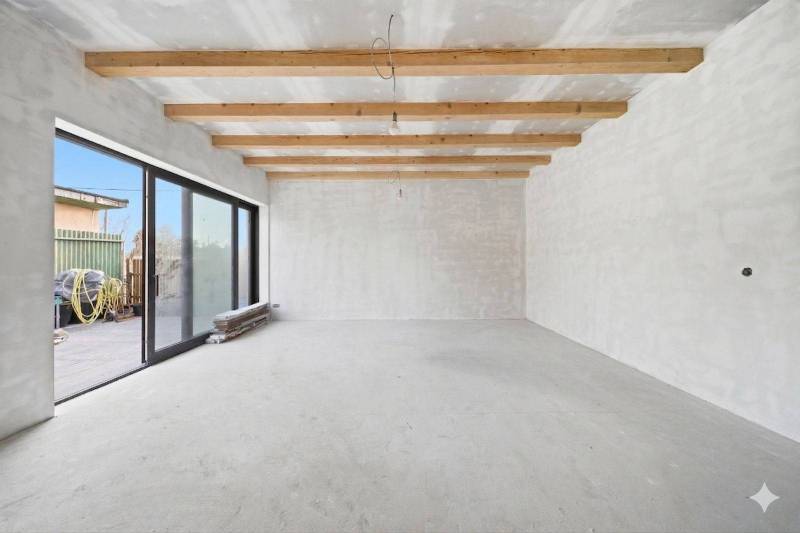 Spacious room in a family house with wooden beams and large glass doors.