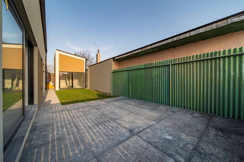 A family house in Poprad with a yard, a green fence, and concrete paving.