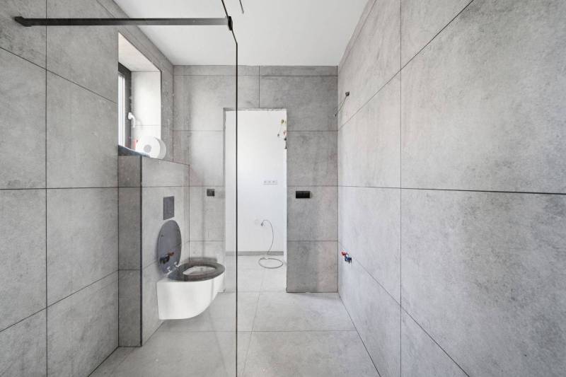 A bathroom in a family house with large-format tiles and a wall-mounted toilet.