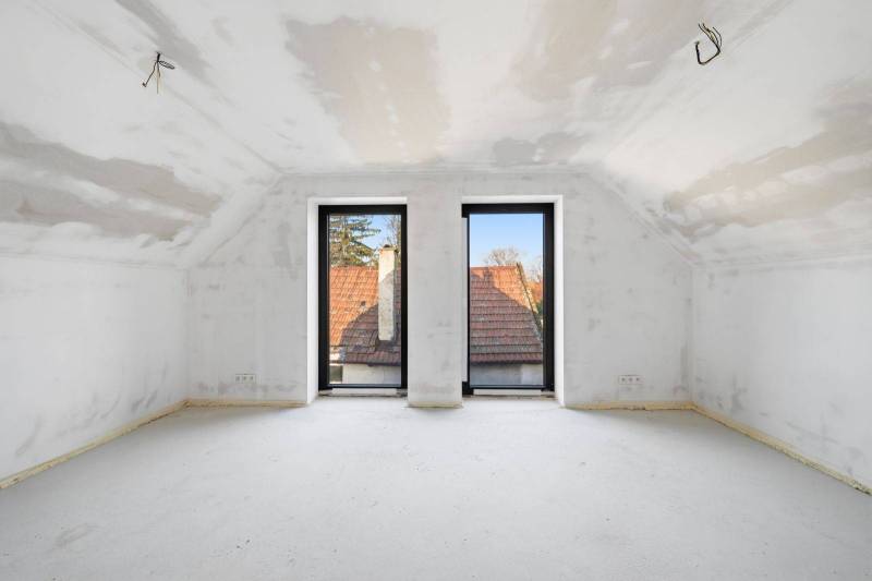 The interior of an attic in a family house with large windows and a view of the rooftops.
