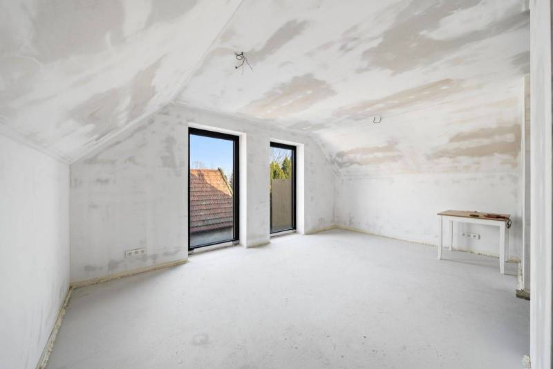 A bright attic room in a family house with neutral tones and large windows.