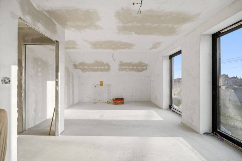 A spacious room in a family house with large windows and an empty floor.