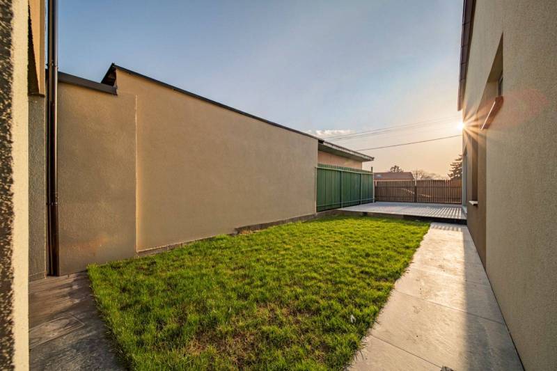 The garden of a family house in Poprad with greenery and a paved walkway.