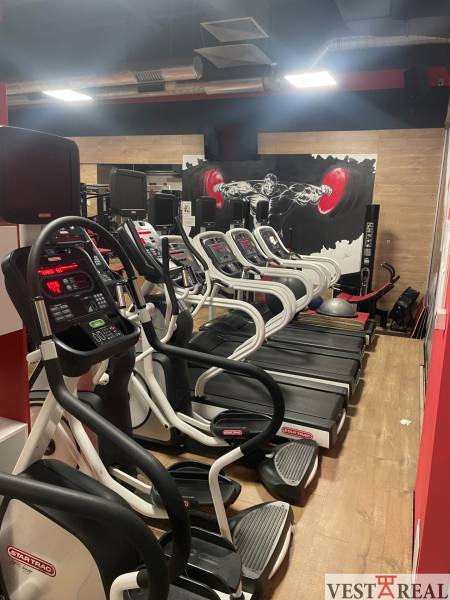 A gym with treadmills and a wooden decor floor in commercial premises.
