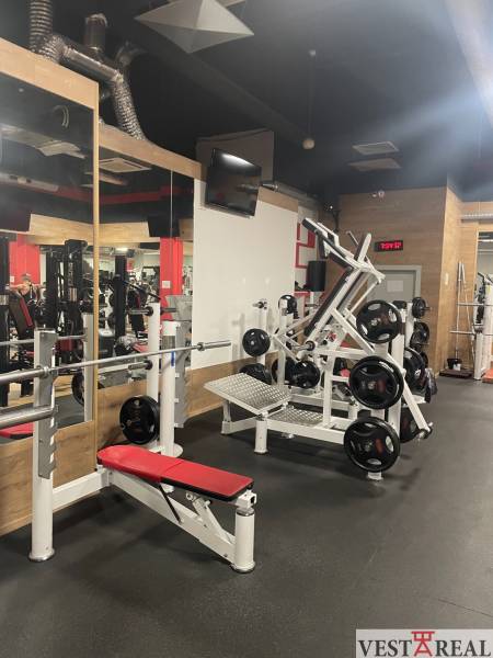 A gym with a bench, dumbbells, and mirrors in commercial premises.