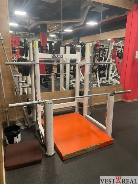 Fitness center with exercise machines and mirrors, floor with wooden decor.