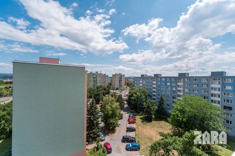 Apartment buildings in the Košice - Západ district, Pražská Street, surrounded by greenery and parked cars.