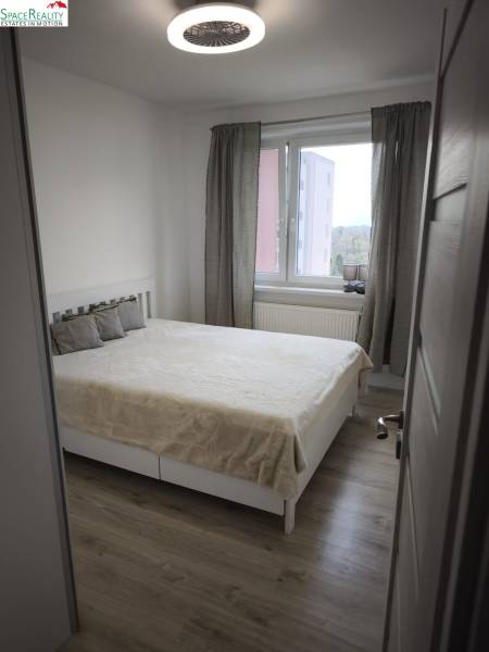 Svetlá spálňa s veľkým oknom a posteľou v 2-izbovom byte.