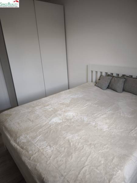 A bedroom in a 2-room apartment with a white wardrobe and a bed with pillows.